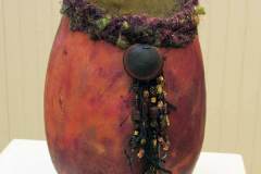 A red gourd crowned by a woven purple circle.