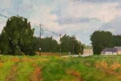 19 – Acrylic painting by J Bowers of a lone white house and green yard back from a country road under a slightly overcast sky.