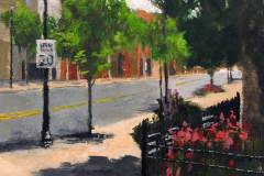 22 – Acrylic painting by J Bowers of a shadowy street scene with a gated flower garden on Gastonia's Main Street.
