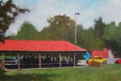 23 – Acrylic painting by J Bowers of a picnic under a red roofed park structure.