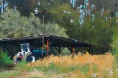 26 – Acrylic painting by J Bowers of a blue tractor under an open-sided shed during summer.