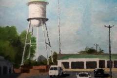 29 – Acrylic painting by J Bowers of a green topped water tower looming over a white strip mall.