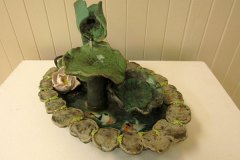 08 Green ceramic fountian with running water splashing over coy fish amid lilly pad edged basin.
