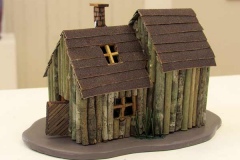 Sculpture of house made of green and brown sticks.