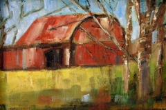 Red barn in a green clearing viewed from small group of trees.