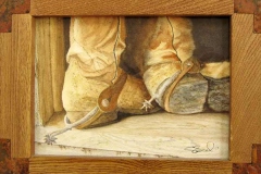 Feet-level view of spurred cowboy boots in a rustic wood frame.