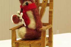 9 - soft sculpture oa a fox wearing a hat resting in a wooden chair