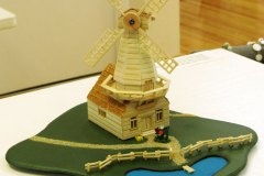 44, 3-d model/miniature of a windmill next to a small pond.