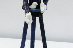 65, a 3D model/sculpture (viewed from the front) of a wooden stick stuture with a realistic head and shoulders of a figure holding 3 white doves.