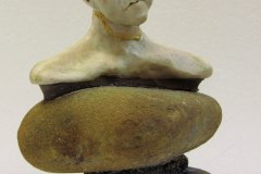 69, a 3D model/sculpture (viewed from the side) of a realistic sorrowful head and shoulders of a figure sitting on 3 stacked semi-smooth rocks.