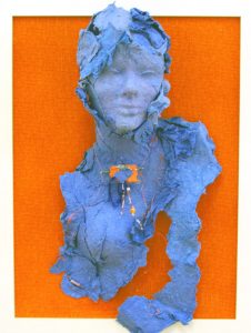 three dimensional paper sculpture of a blue female figure emerging from an orange cloth background by Janet Kaufman