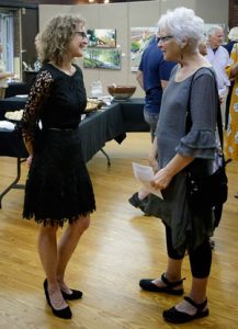 Artist Anne Harkeness greeting a woman at her exhibit reception