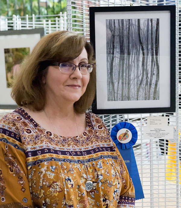 Ellen Devenny on front of her photo of trees