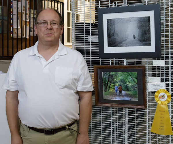 Norman Stringer in front of his photo of child in the woods