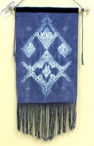 woven fiber art panel of white design on blue background with fringe by Sue Helmken.