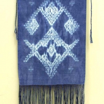 woven fiber art panel of white design on blue background with fringe by Sue Helmken.