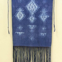 woven fiber art panel of white design on blue background with fringe by Sue Helmken.