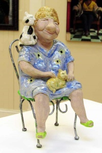 clay sculpture of a woman in chair with a cat on her lap by artist Janet Sims.