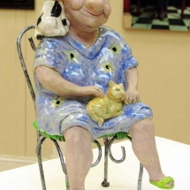 clay sculpture of a woman in chair with a cat on her lap by artist Janet Sims.