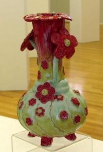 reen pottery vase with deep red flowers and red feet by artist Renee Matthews.