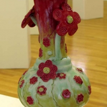 reen pottery vase with deep red flowers and red feet by artist Renee Matthews.