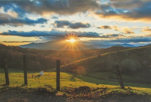 Appalachian field below a sunset behind the mountain range photographed in color by photographer Robert Webb.