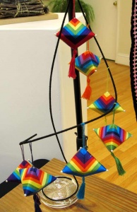 Rainbow color-striped spinning top-shaped ornaments with single tassels by artist Sue Helmken.
