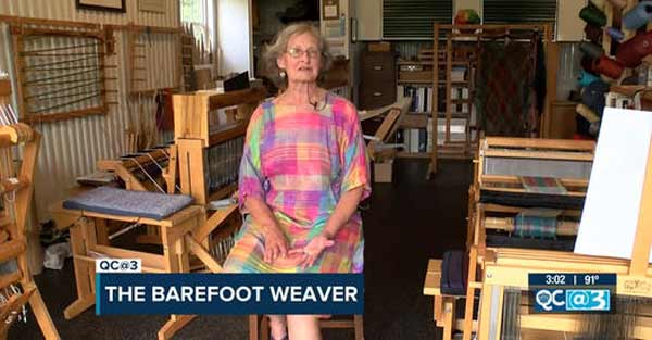 Sue Helmken, while barefoot, site in front of her looms for WBTV interview titled The Barefoot Weaver.