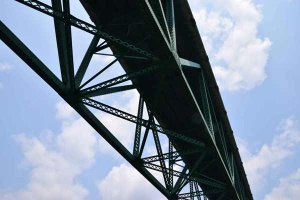 44 upward view of steel bridge gurders against a blue sky.
