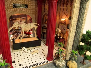 45b detail of miniature room sculpture of museum room with tiled floor displaying animal skeletons.