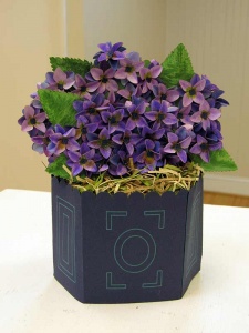 Paper cut work of purple hydrangeas in a blue vase with light green line accents.