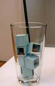 Pale blue colored ice cubes, each containing a snow scene, snow flakes, rein deer, wooden fence.