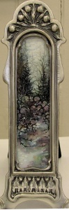 Art nouveau frame around a watercolor of a snowy path in the woods.