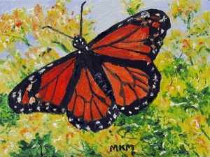 MRed and black monarch butterfly against green bushes and blue sky.