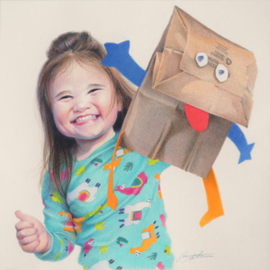 Little girl in turquoise pajamas holding up a paper bag hand puppet.
