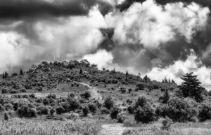 Looking upward at a hill with momentous clouds above.