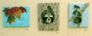 3 quilted, applique works: 1 with fall leaves, the second of a racoon emerging from a tree trunk, and the last depicting a nest in a single tree branch.