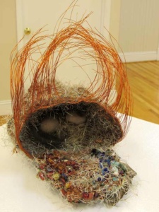 copper wire sculpture of a birds next with 2 eggs hiiden in the back of the opening.