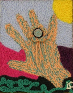 an orange and green hand with a floral ring created in thick crochet yarns.