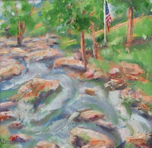 a US flag erected on the bank of a rushing rocky creek.