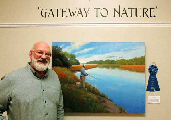 Artist Todd Baxter with his oil painting of a man fishing at a calm blue pond.