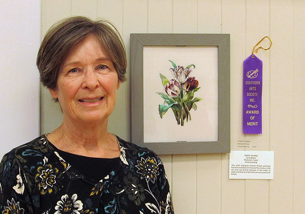 ARtist Janet Baxter with her hand stitched rendering of purple tulips and green leaves.