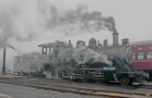 Photograph an old style train profusely emitting stea,m.