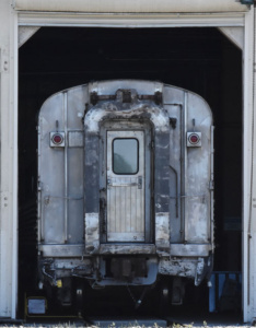 Photography of a frontal view of a modern train emergin from a dark tunnel.