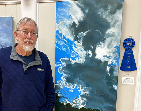 Artist Dennis Huntley with his artwprkd of a cloudscape.