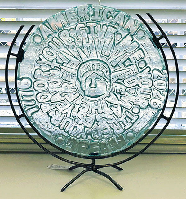 clear glass scolpture with the head of the Staue of Liberty in the center.