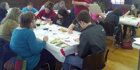 class of adult students working on colored pencil artworks.