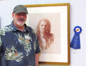 artist todd baxter in front of his first place drawing of a woman in colored pencil