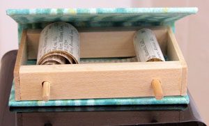 two decorative scrolls inside a wooden box covered in artists paste papers